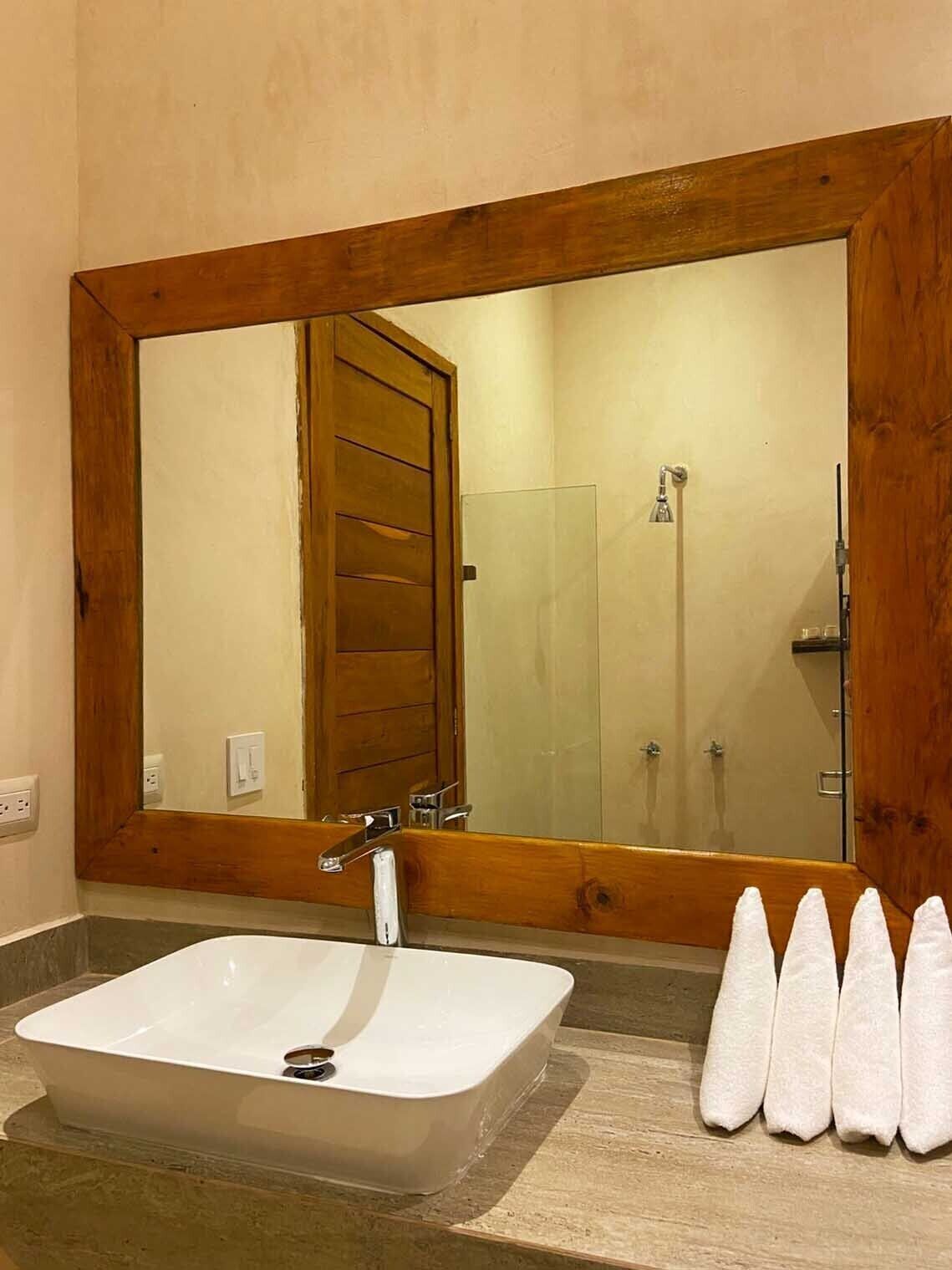 A bathroom with a large mirror, a rectangular sink, and a shower area.