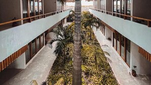 Un couloir d’hôtel avec une allée centrale bordée de chambres dotées de grandes fenêtres et de toits de chaume.
