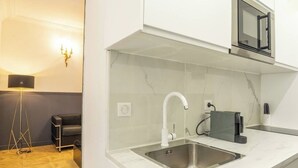 A modern kitchen with a white countertop, a stainless steel sink, and a black coffee machine. - MAGNIFICENT APARTMENT NEAR THE EIFFEL TOWER (Paris)