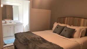 Een slaapkamer met een bed, een zacht tapijt, een nachtkastje en een spiegel.