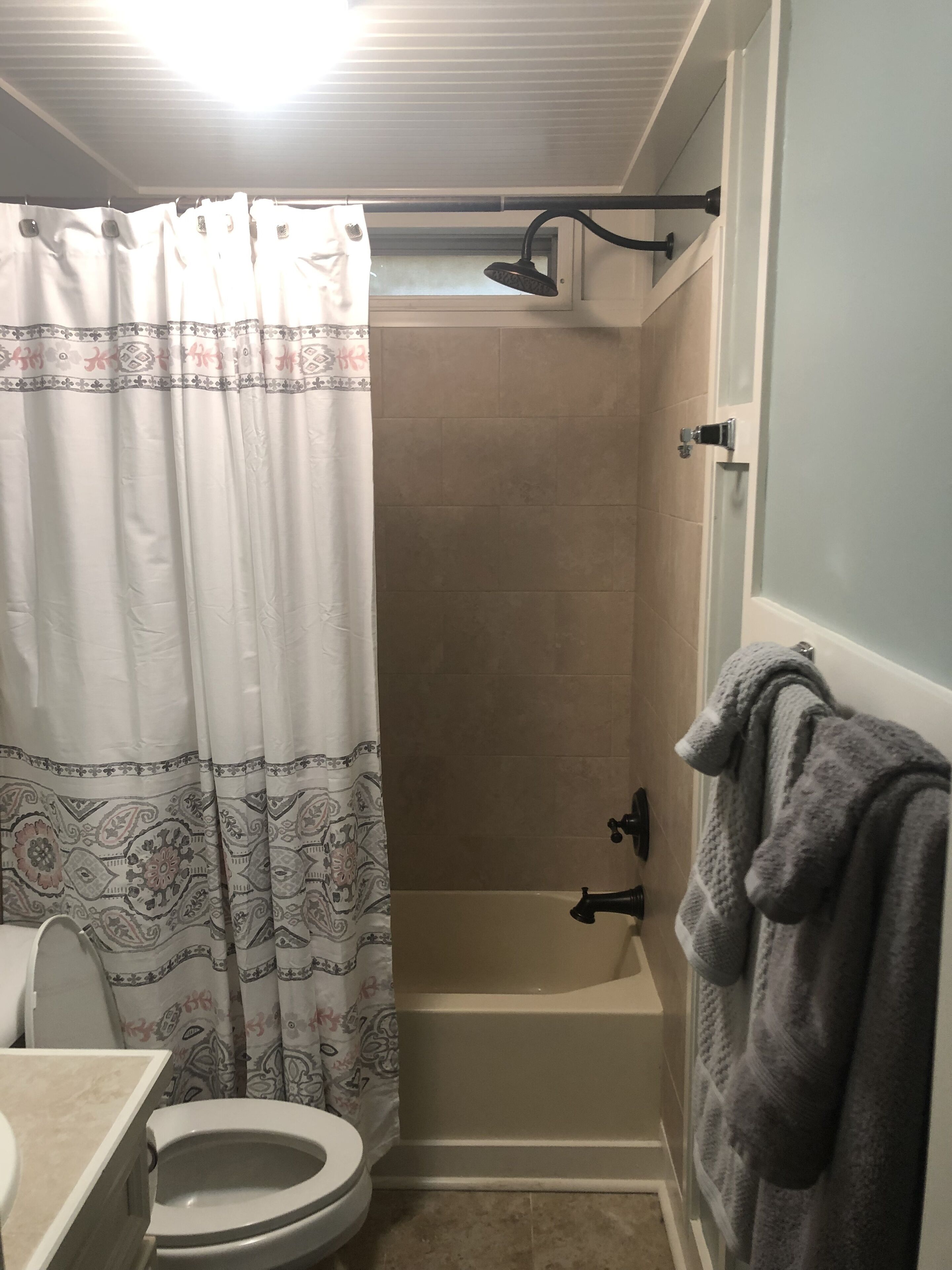 A bathroom with a shower, toilet, and towel rack.