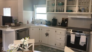 Een keuken met witte kasten, een roestvrijstalen oven en een raam boven de spoelbak.