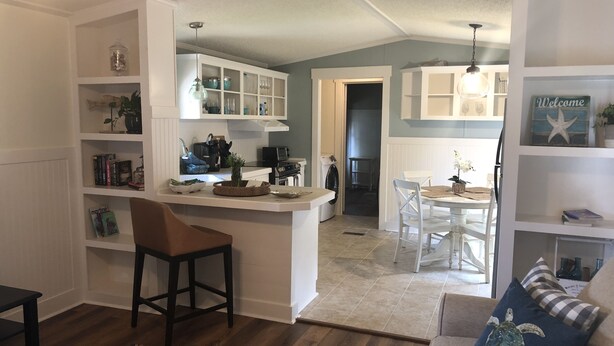 Een moderne keuken met witte kasten, een centraal eiland en een eethoek met witte stoelen.