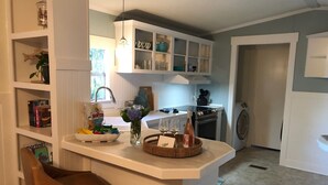Een keuken met witte kasten, een bar met een bruine stoel en een spoelbak.