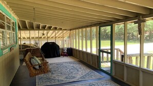 A covered porch with a swing, a large rug, and a view of a grassy area. - LOTS of parking for vehicles and boats. Large porch with swing and table, chairs (Steinhatchee)