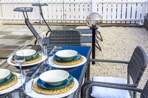 Comedor con una mesa dispuesta para cuatro personas, con individuales tejidos, platos azules y blancos, y vasos de vidrio.