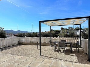 Un patio al aire libre con pérgola, zona de estar y vistas del paisaje circundante.
