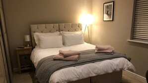 A neatly made bed with a tufted headboard, a bedside lamp, and a framed picture on the wall. - Romantic Lodge on the Pilgrims way, Hollingbourne nestled in the Northdowns (Hollingbourne)