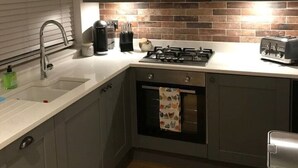 A modern kitchen with grey cabinets, a stainless steel sink, a gas stove, and a microwave. - Romantic Lodge on the Pilgrims way, Hollingbourne nestled in the Northdowns (Hollingbourne)