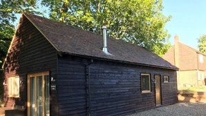 A wooden building with a pitched roof, a chimney, and a gravel driveway. - Romantic Lodge on the Pilgrims way, Hollingbourne nestled in the Northdowns (Hollingbourne)