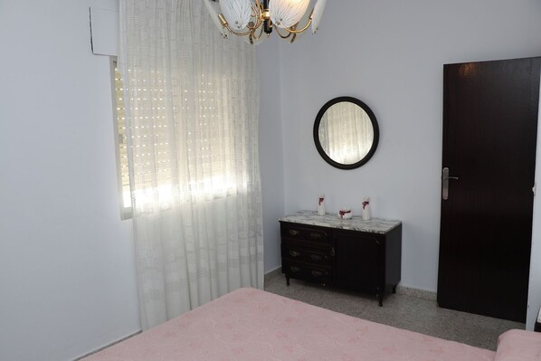 Un dormitorio con cama, cómoda, espejo y puerta.