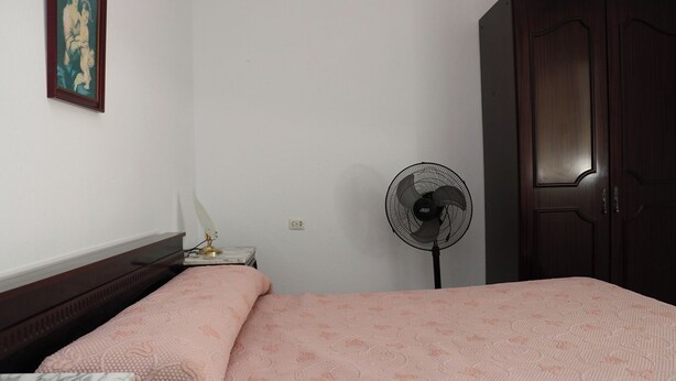 A bedroom with a bed, a desk, a chair, a standing fan, and a wardrobe. - Central apartment on the first floor (CONIL DE LA FRONTERA)