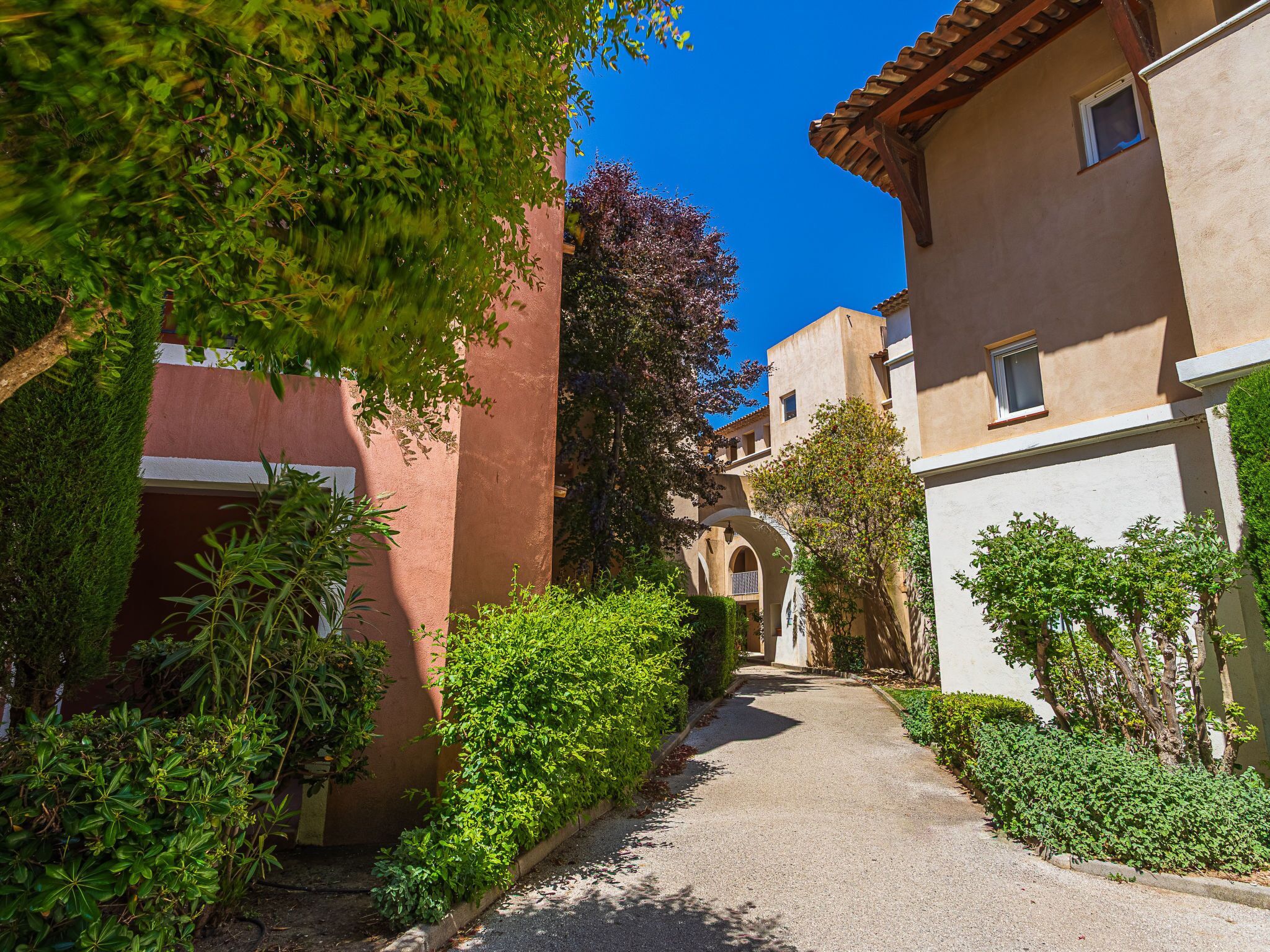 Une ruelle étroite, bordée d’immeubles, avec un ciel bleu dégagé au-dessus.