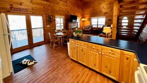 Een houten chalet van binnen met een keuken, een eethoek en een balkon.
