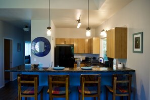 Una cocina moderna con armarios de madera, un refrigerador negro y una isla azul con taburetes de bar.