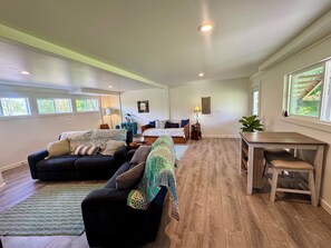 A spacious living area with a sofa set, a dining table, and a view of a staircase.