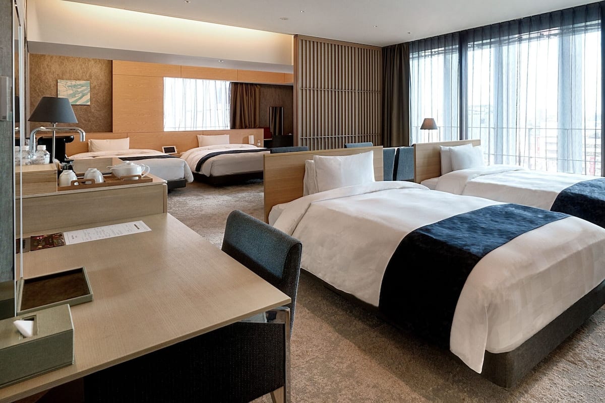 A hotel room with two beds, a desk, and a chair.