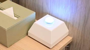 A tissue box and a white device with a blue light on a wooden surface.