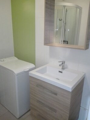 Un baño con un lavabo blanco, un mueble de madera y un espejo sobre el lavabo.