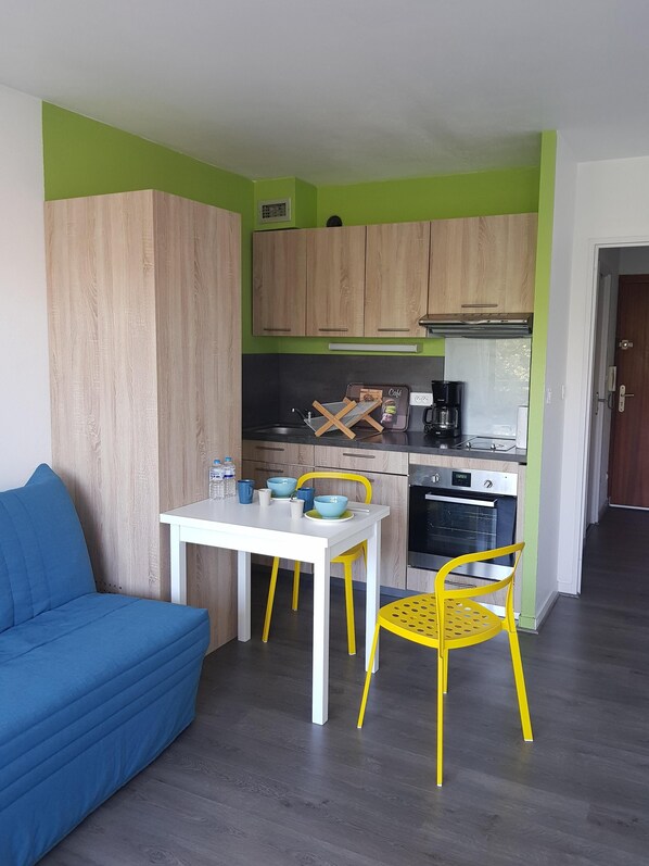 Una cocina pequeña con armarios de madera, una mesa blanca y sillas amarillas.
