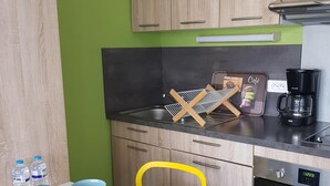 Una cuina moderna amb armaris de fusta, un taulell negre, una cafetera i una taula preparada amb bols i tasses.