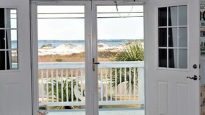 A room with a view of the beach through a white door with glass panels.