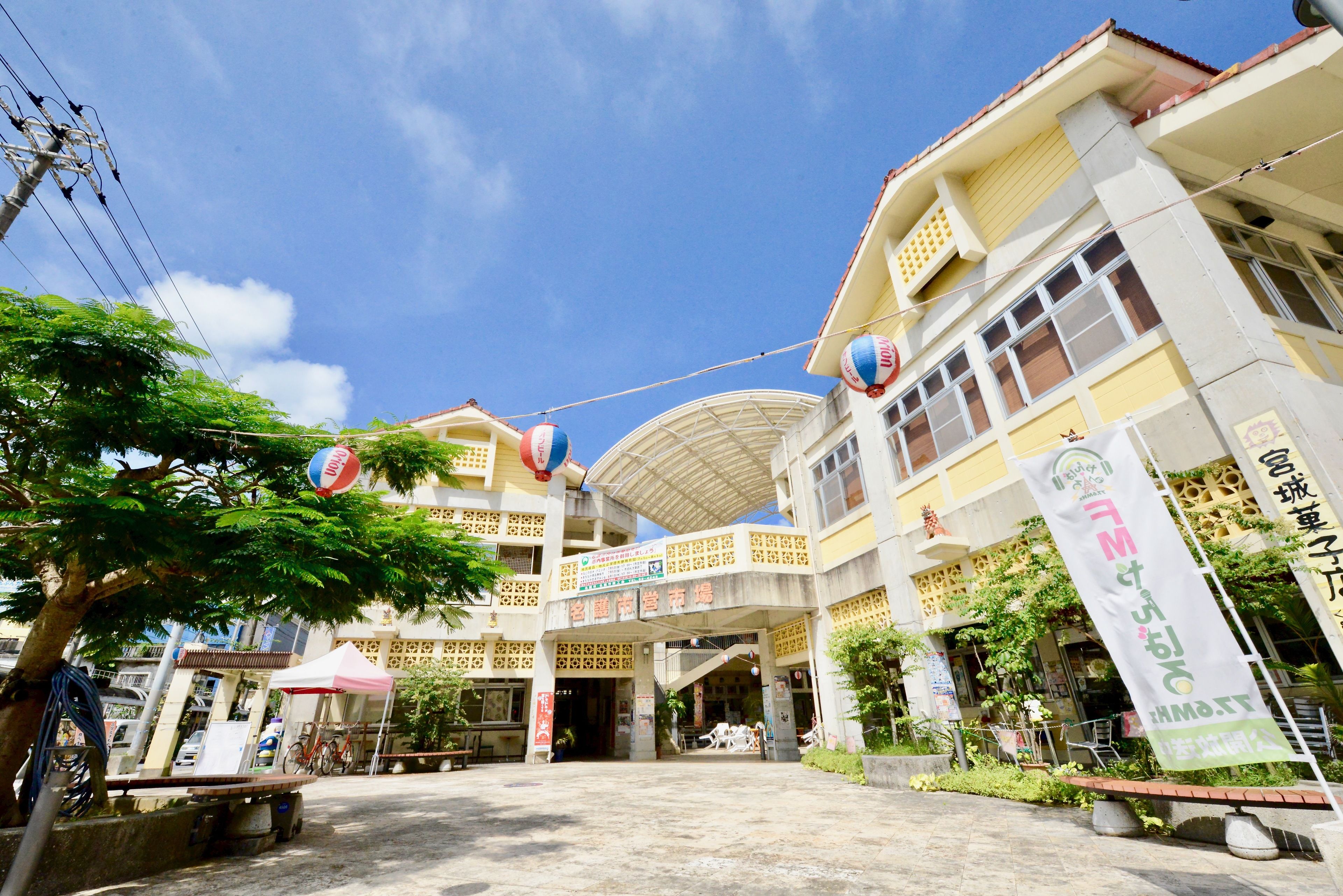 A multi-story building with a covered entrance, outdoor seating, and a bicycle parked outside.