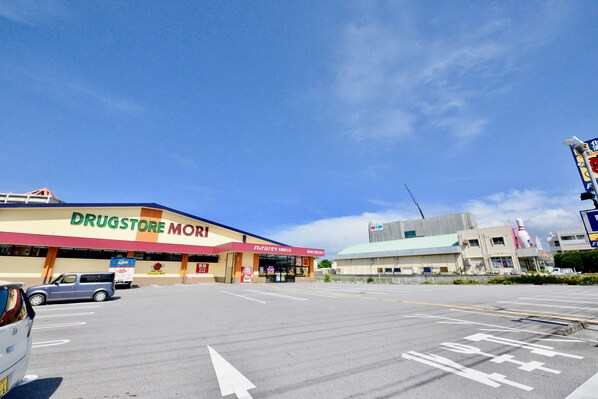A drugstore with a clear sky and a parking lot in front. - Adan Hotel (Nago)
