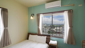 A bedroom with a bed, a chair, a window with curtains, and an air conditioning unit. - Adan Hotel (Nago)