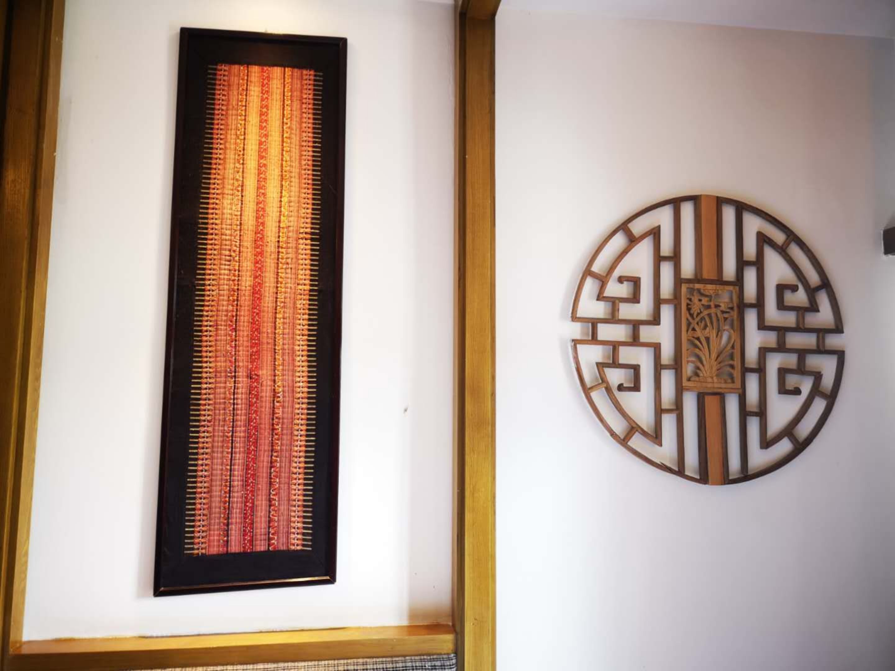 A framed textile artwork and a decorative wall piece.