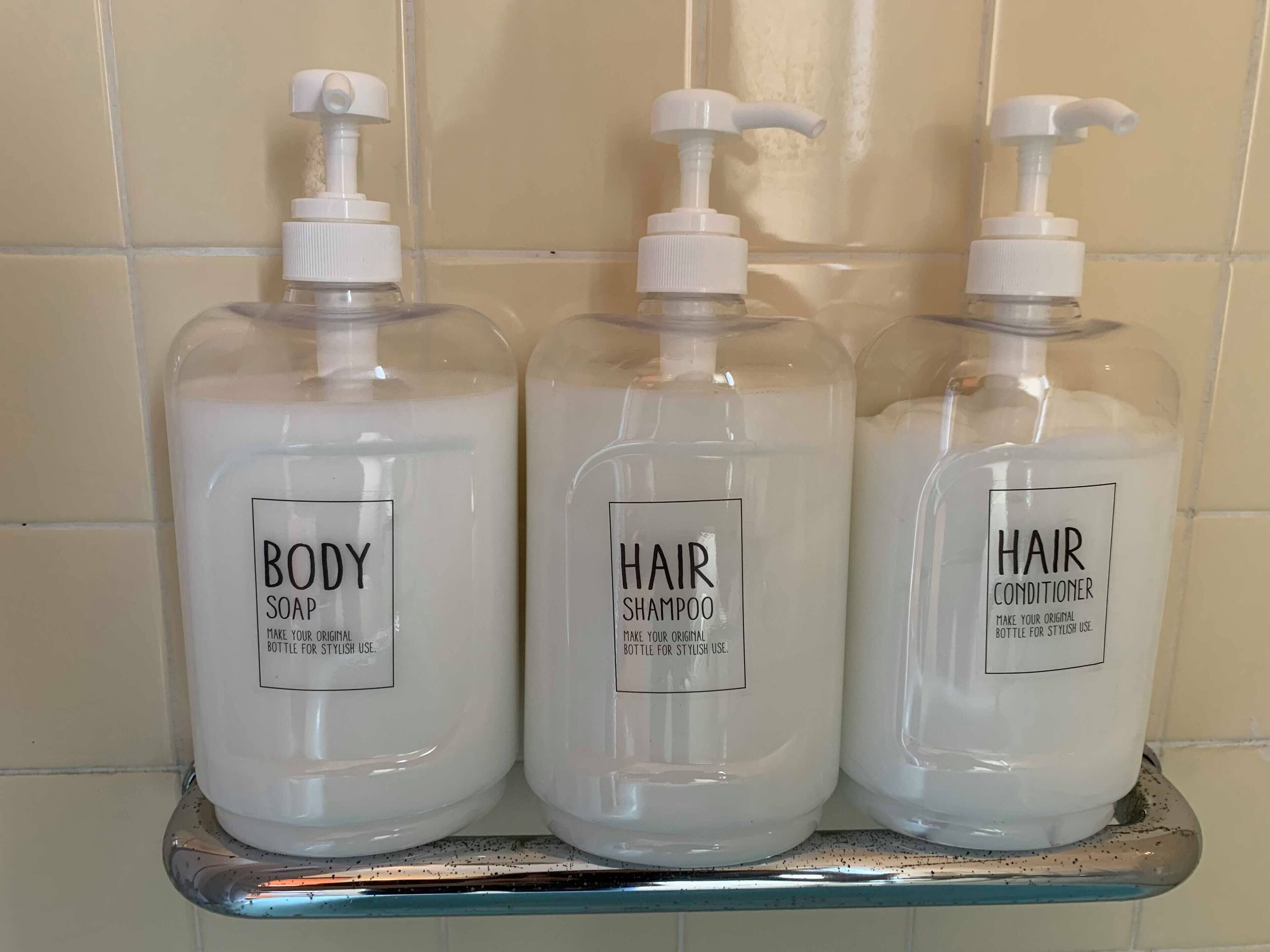Three bottles of body soap, hair shampoo, and hair conditioner on a shelf.