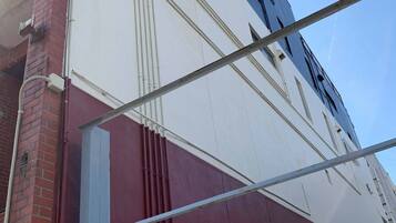 Un edificio con fachada blanca y roja, una ventana visible y una estructura metálica.