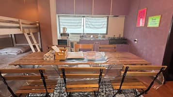 A compact kitchen with a window, a bunk bed, and a dining table with chairs.