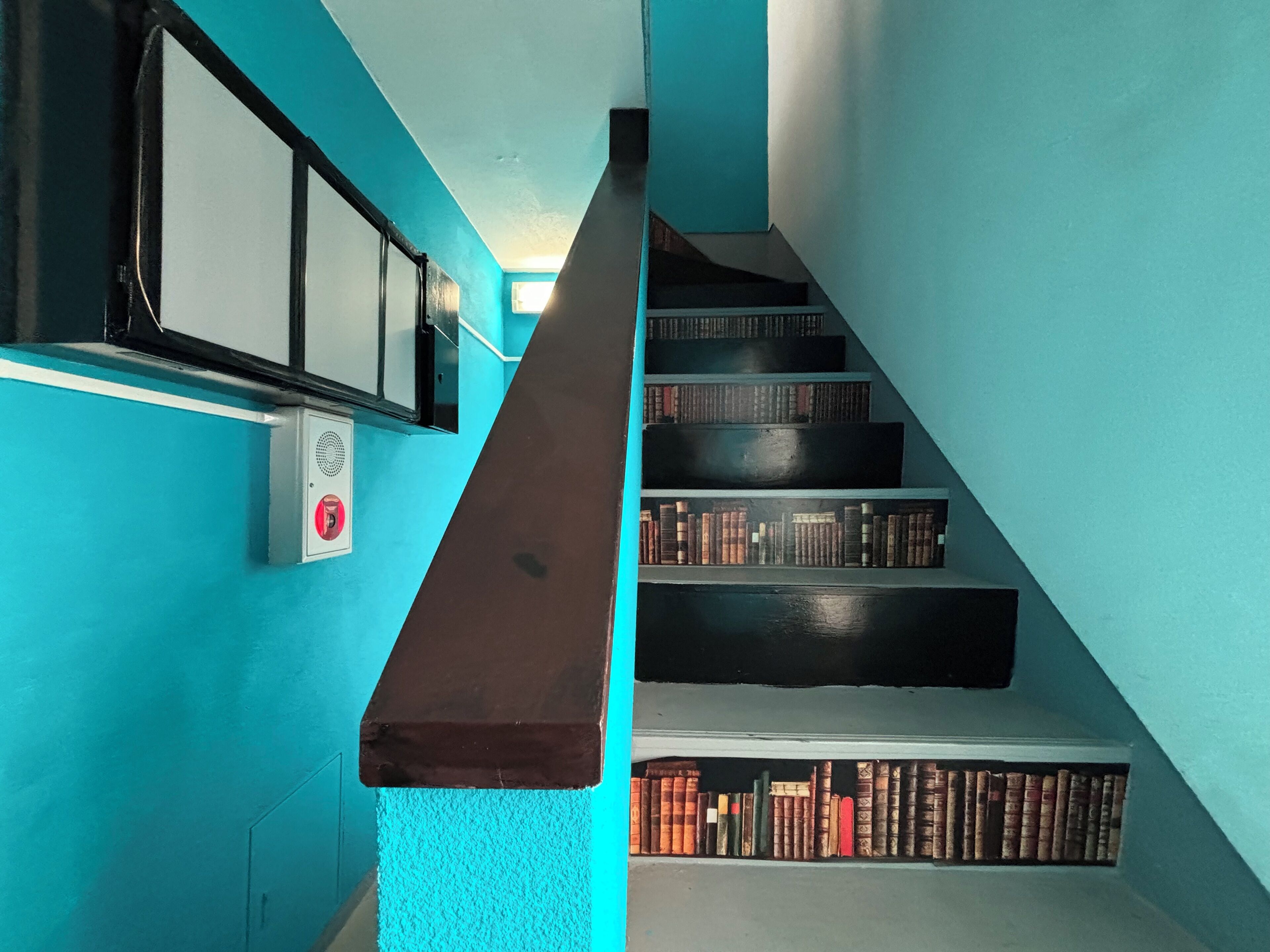 A staircase with a blue wall and a white handrail.