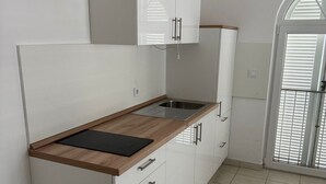 Une cuisine moderne avec des meubles blancs, un plan de travail en bois et un évier en acier inoxydable.