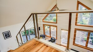 Una escalera de madera con barandillas de metal y ventanas amplias que ofrecen vistas al exterior.