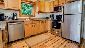 Una cocina moderna con armarios de madera, electrodomésticos de acero inoxidable y una ventana con vistas a la vegetación.
