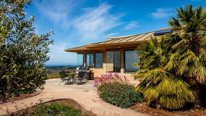 Une maison moderne dotée d’un patio, d’un espace salon extérieur et offrant une vue sur le paysage.