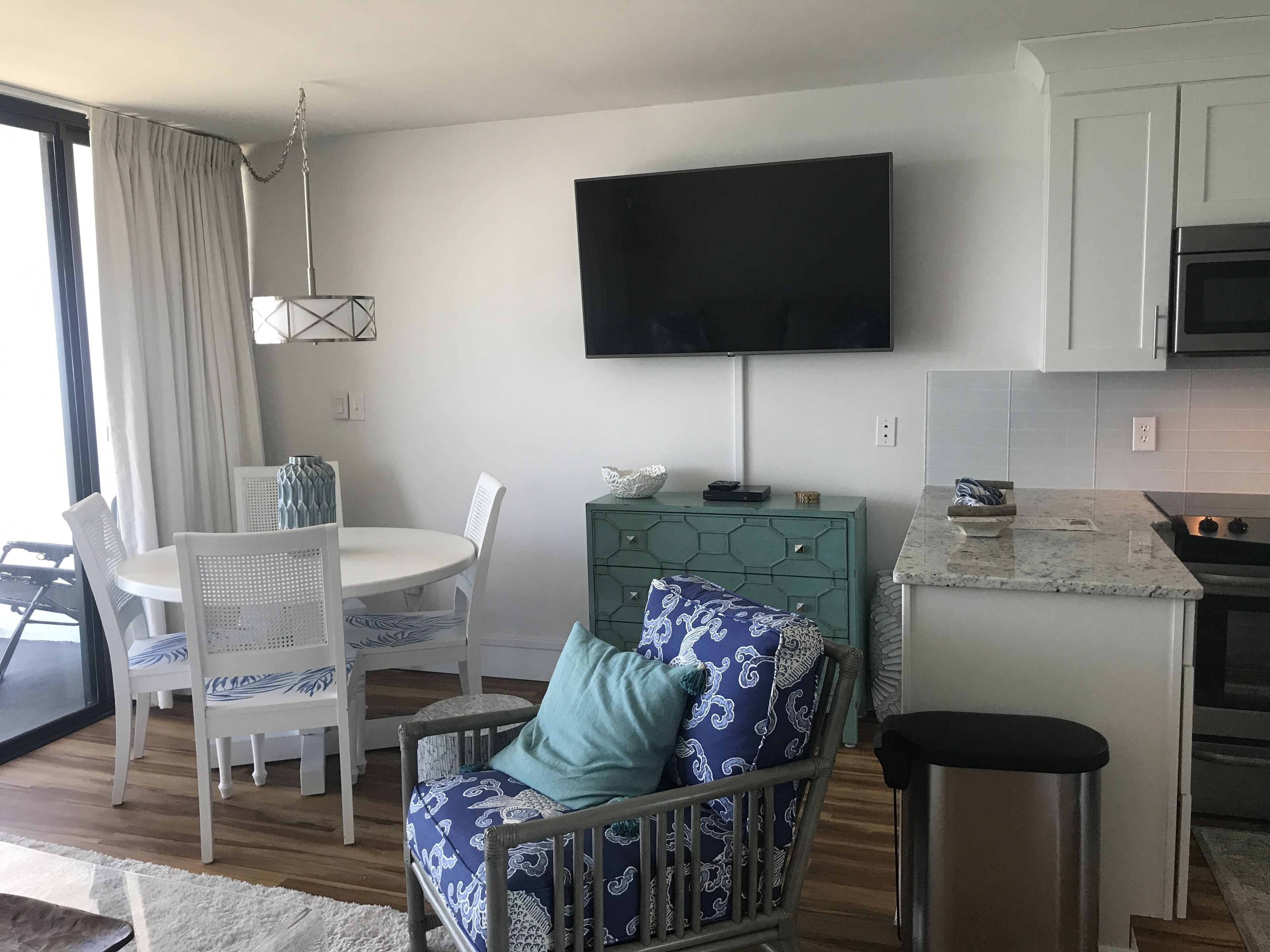 Ein modernes Wohnzimmer mit Essbereich, einem an der Wand befestigten Fernseher und einer Küche mit Mikrowelle.