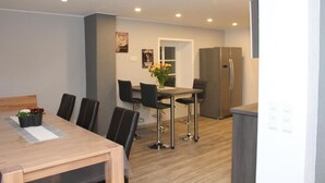 Un comedor moderno con una mesa de madera, sillas negras y un florero con flores.