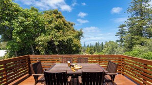 A wooden deck with a table and chairs, surrounded by trees. - Bucks Point House (Norfolk Island)