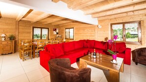 L’intérieur d’un chalet en bois, avec un canapé rouge, une table à manger et des chaises.