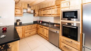 Une cuisine moderne avec des meubles en bois, des appareils en acier inoxydable et un plan de travail noir.