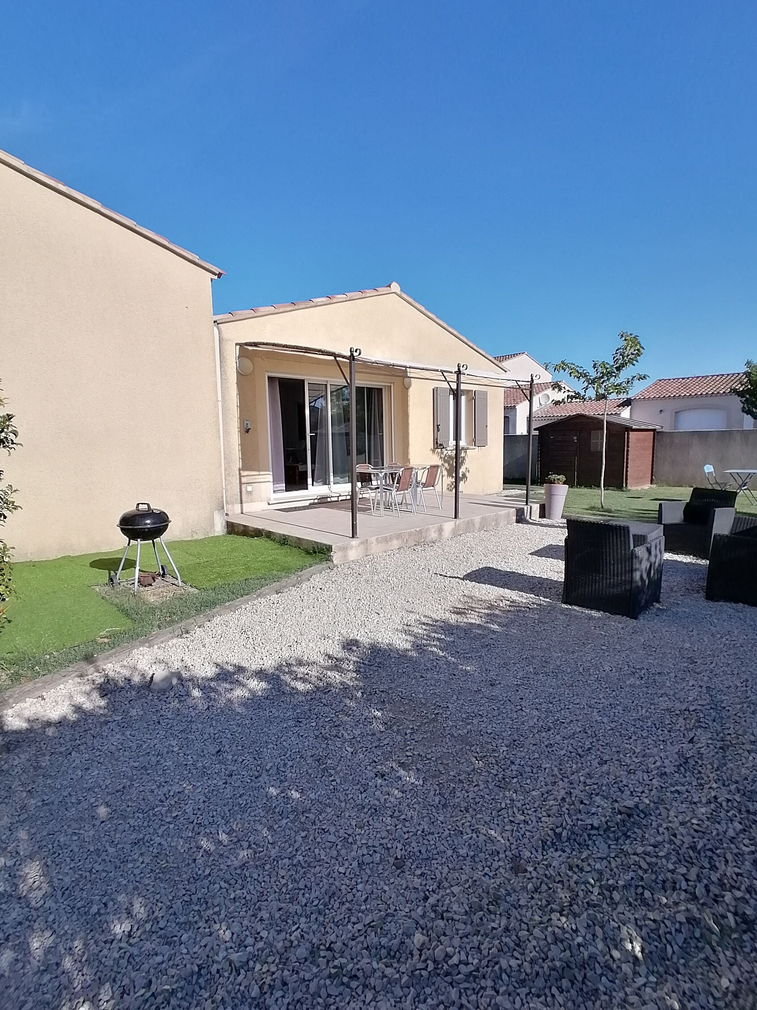 A residential property with a patio area, outdoor seating, and a barbecue grill.