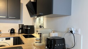 A modern kitchen with a black toaster, a coffee maker, and a kettle on the counter. - Apartment type villa in Sanary sea view, 150m from the beach with Jacuzzi plus parking (Sanary-sur-Mer)