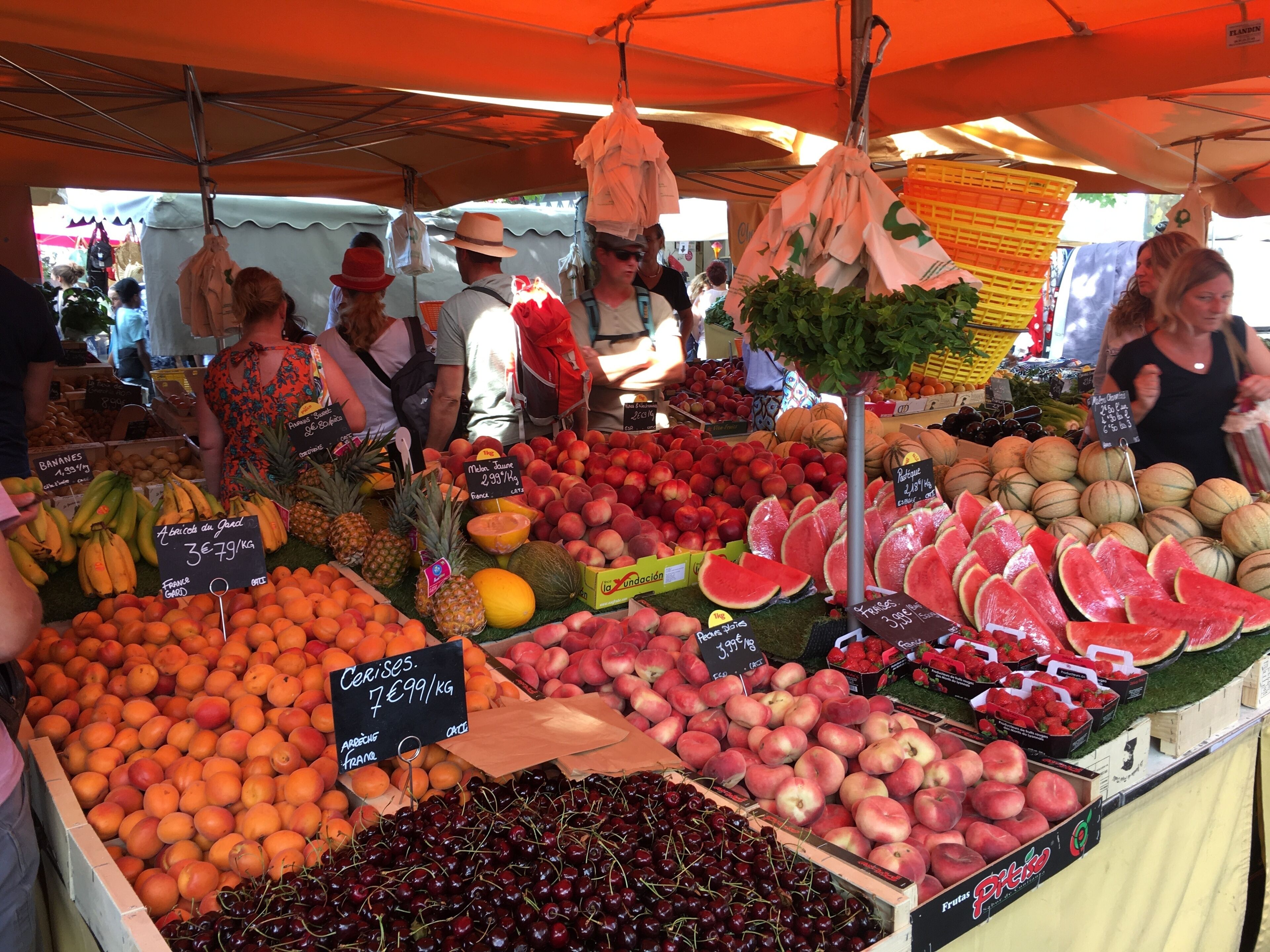 Un puesto de mercado con frutas variadas como manzanas, naranjas y cerezas a la vista.