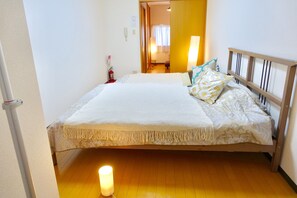 Ein ordentlich bezogenes Bett mit einem gemusterten Überwurf, einer Nachttischlampe und einem Holzkopfende.