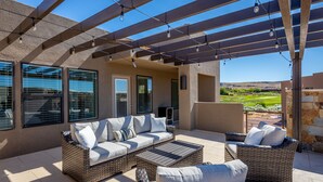 An outdoor patio with wicker furniture, a pergola with string lights, and a view of the landscape. - Spacious 4BR Sleeps 12 - 2 Rec Rooms on the 18th (St. George)