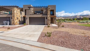 A modern two-story house with a stone facade, a covered patio, and a view of a mountainous landscape. - Spacious 4BR Sleeps 12 - 2 Rec Rooms on the 18th (St. George)
