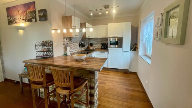 Una cocina moderna con armarios blancos, una isla de madera y un salpicadero de piedra.